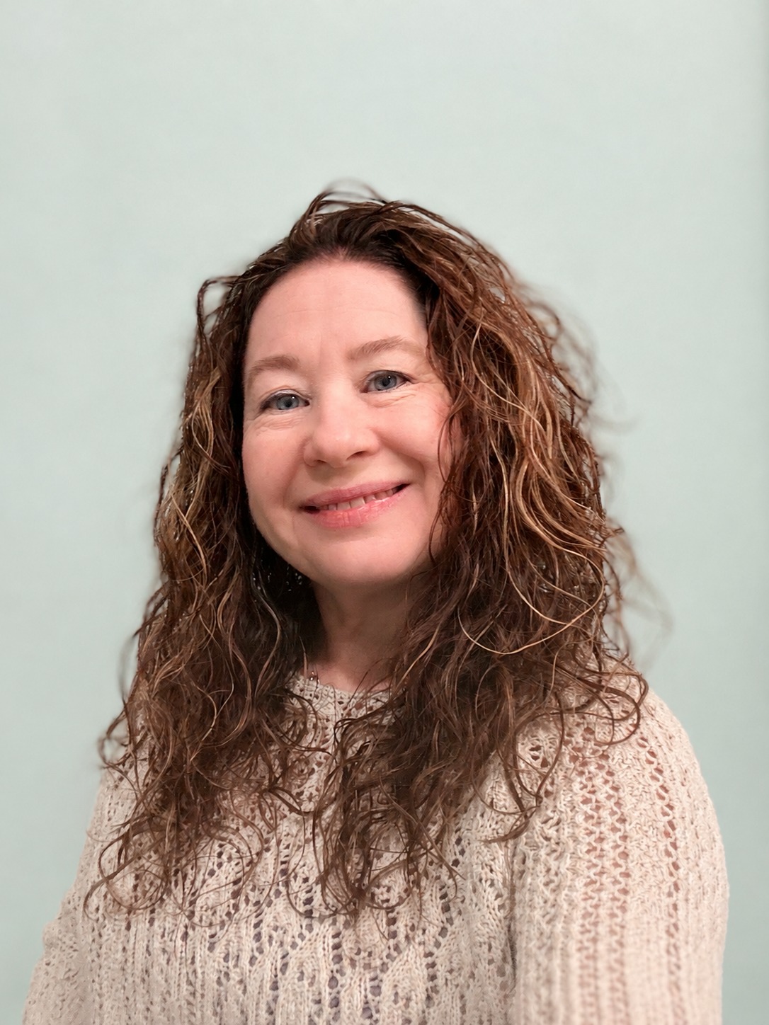 Ginny Hendon, founder of Ginny’s Helping Hands LLC, smiling against a pale green background